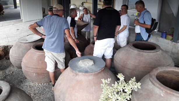 A group of people standing around large clay pots, possibly in a workshop or outdoor setting. - Tzionis Petroktisto Holiday Stonehouse (Lympia)