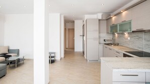 Une cuisine moderne avec des armoires blanches, un plan de travail en marbre et des spots encastrés au plafond.