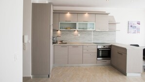 Une cuisine moderne avec des meubles en bois clair, un plan de travail en marbre et des appareils électroménagers intégrés.