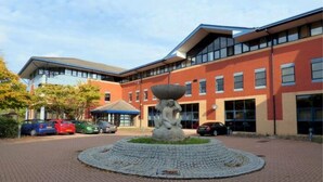 A building with a central courtyard featuring a stone sculpture, surrounded by a brick pathway. - Hamilton Grace - The Quadrant (Swindon)