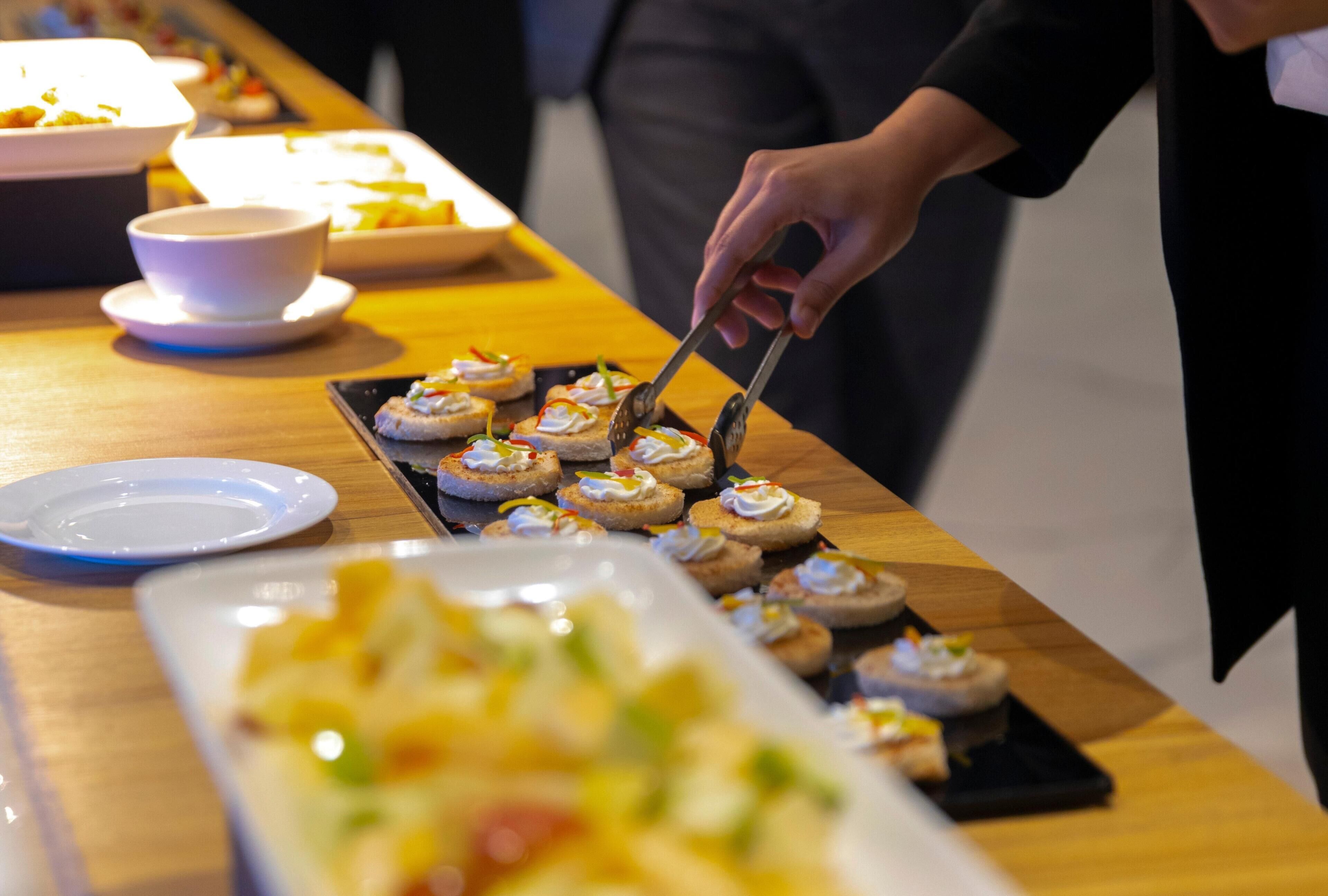 Una mesa de buffet con diversos platos, incluyendo una fuente rectangular grande y platos más pequeños con comida.