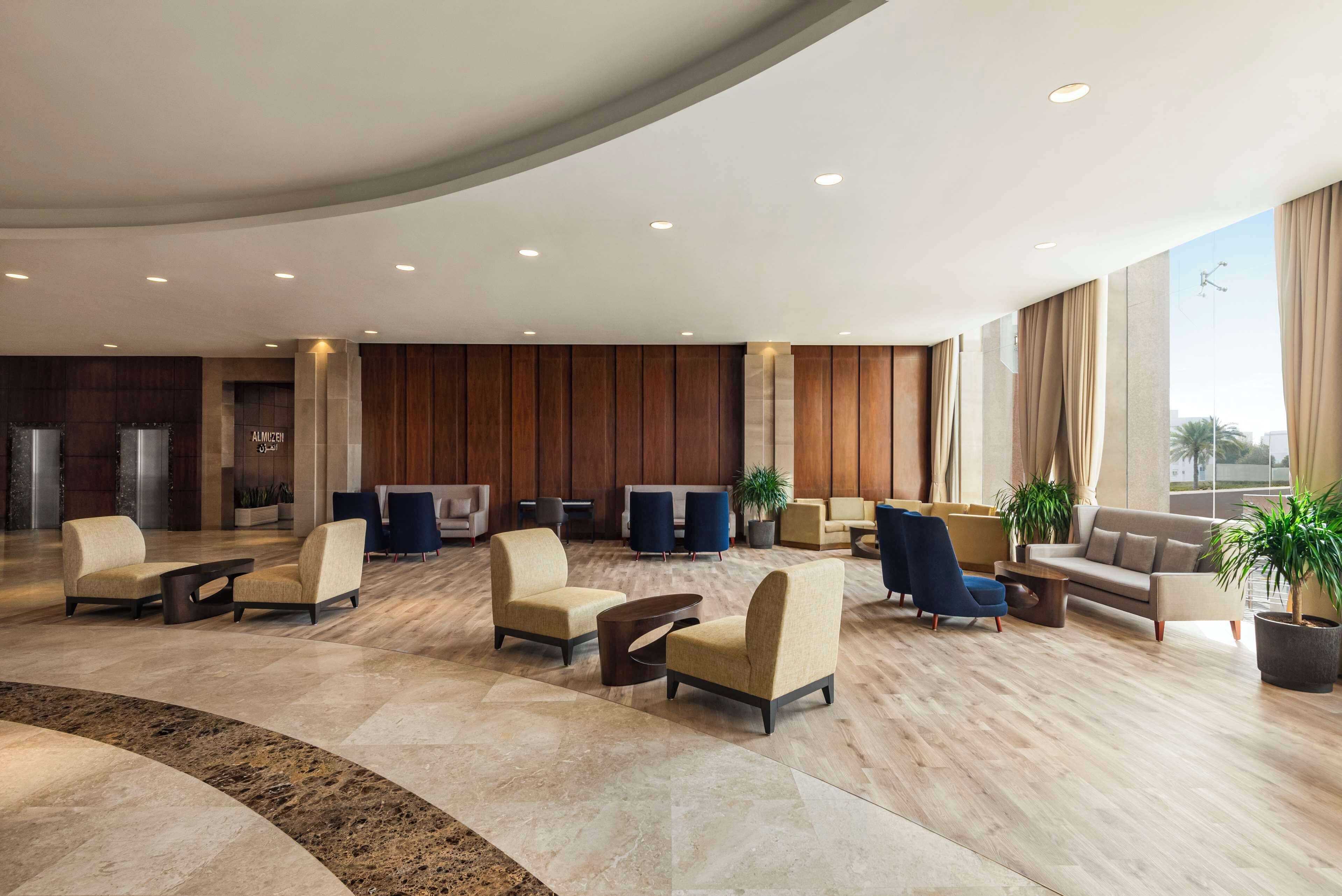 A spacious lobby with a curved ceiling, seating areas, and large windows.