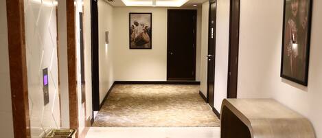 A hotel corridor with a marble floor, a bench, and a trash bin.