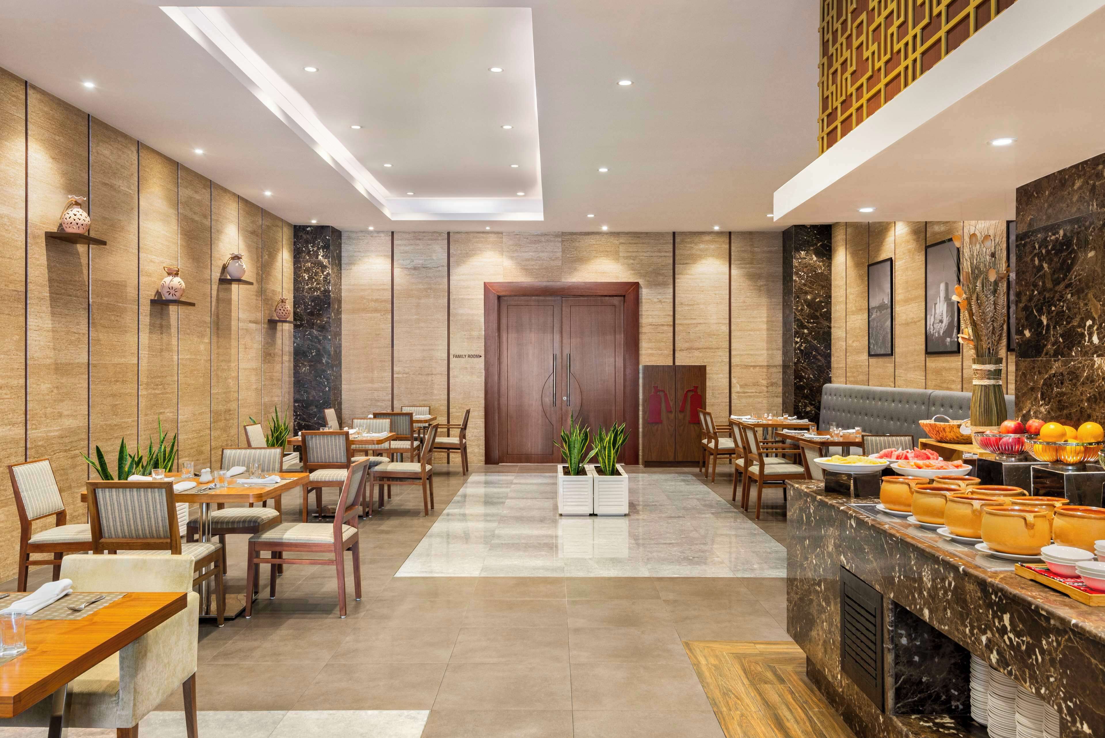 Un hall d’hôtel comprenant un espace repas, des coins salon et un buffet.