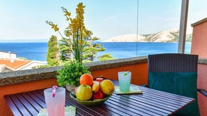 Ein Balkon mit Tisch für zwei Personen, mit Obstschale, zwei Getränken und einer Topfpflanze.