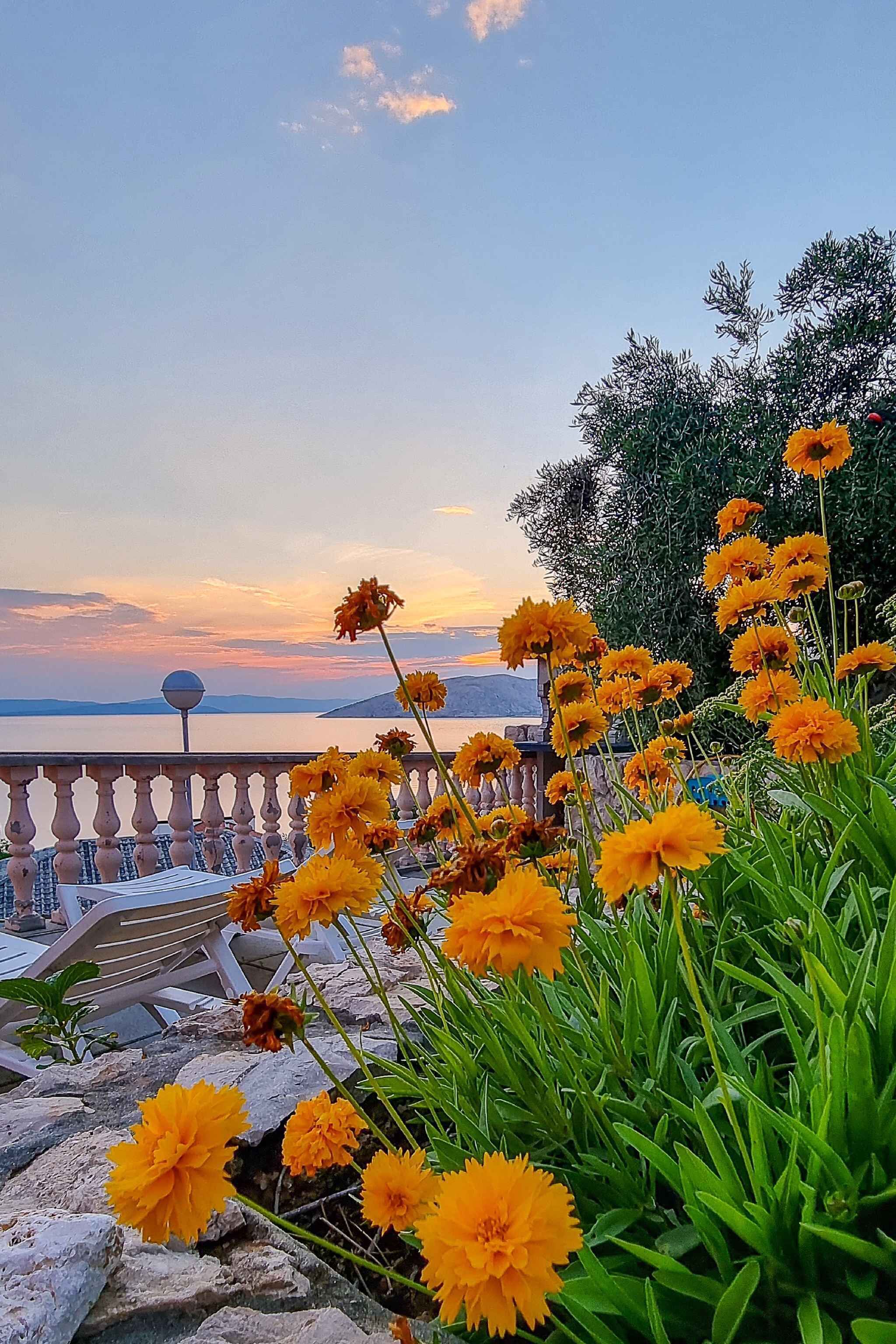 A balcony with a railing overlooking a body of water and a sunset.