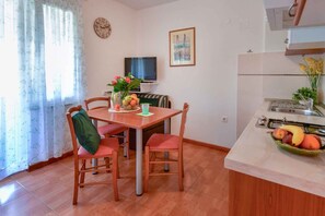 Una cocina compacta con comedor, televisor y un reloj en la pared.