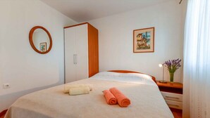 Ein Hotelzimmer mit Bett, Kleiderschrank, Spiegel, einem gerahmten Bild und einer Vase mit Blumen.