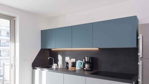 Una cocina moderna con armarios azul oscuro, una encimera negra y un horno empotrado.