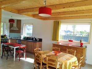 Eine Küche mit Holzschränken, einem Esstisch mit Stühlen und einem Fenster mit Vorhängen.