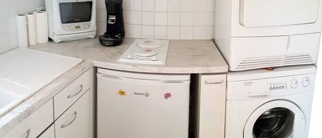 A compact kitchen with a microwave, coffee maker, dishwasher, and washing machine.