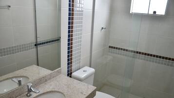 Casa de banho com duas pias, sanita e cabine de duche em vidro.