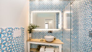 Un baño con un estampado geométrico de azulejos, un lavamanos blanco y un espejo sobre él.