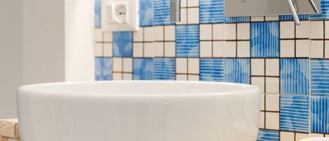 A white vessel sink on a wooden countertop with a blue and white tiled backsplash.