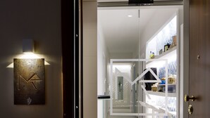 Un pasillo moderno de hotel con una pared de vidrio, una escalera a la vista y un elemento decorativo en la pared.