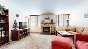 A living room with a fireplace, a television, a bookshelf, and a sofa.