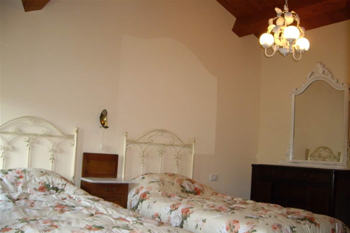 A bedroom with two beds, a wooden dresser, a mirror, and a chandelier.