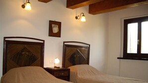 A room with two beds, wooden headboards, a nightstand with a lamp, a framed picture on the wall, and a window. - La Quercia del Saggio (Senigallia)