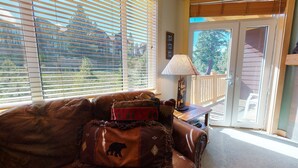 A living room with a leather couch, a lamp, and a view through a window with blinds. - Sunstone 208 Updated Ski-In Ski-Out Condo At Sunstone Lodge with Great Complex Amenities by RedAwning (Mammoth Lakes)