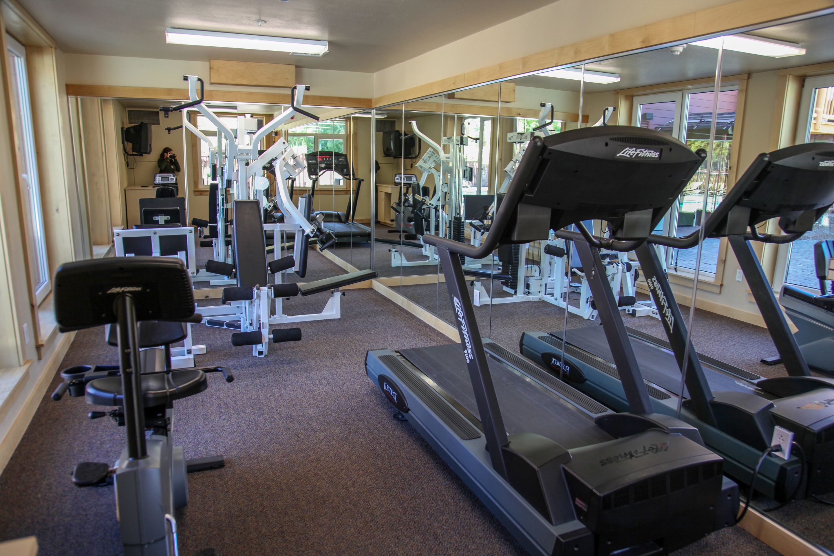 A gym with treadmills, weight machines, and a mirrored wall.