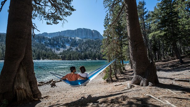 A hammock between two trees overlooking a lake with mountains in the background. - Sunstone 208 Updated Ski-In Ski-Out Condo At Sunstone Lodge with Great Complex Amenities by RedAwning (Mammoth Lakes)