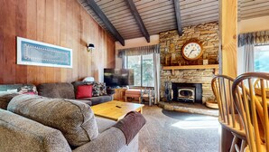 A cozy living room with a stone fireplace, wooden walls, and a large television. - Discovery 4 108 Great Complex Amenities, Close to Canyon Lodge by RedAwning (Mammoth Lakes)