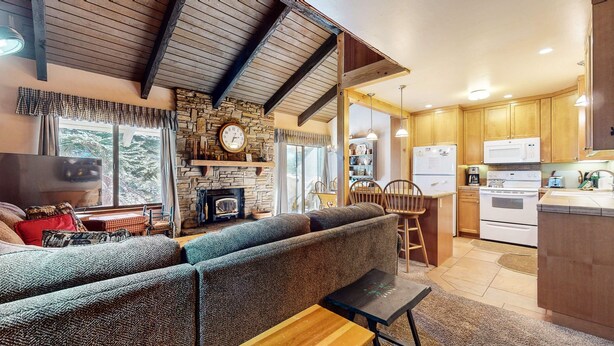 A cozy living room with a sofa, a fireplace, and a kitchen area with wooden cabinets and appliances. - Discovery 4 108 Great Complex Amenities, Close to Canyon Lodge by RedAwning (Mammoth Lakes)