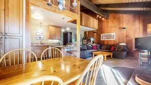 A cozy living area with a wooden dining table, chairs, a sofa, and a television. - Discovery 4 108 Great Complex Amenities, Close to Canyon Lodge by RedAwning (Mammoth Lakes)