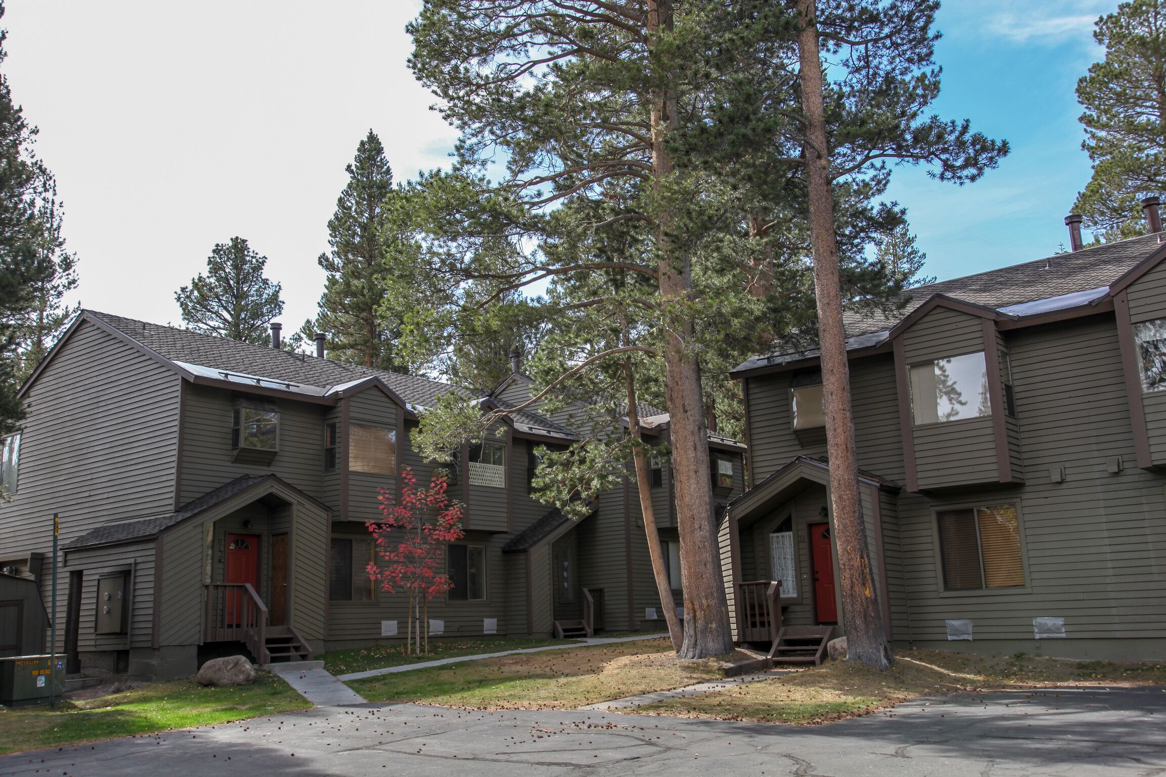 A row of two-story houses with a central walkway, surrounded by tall trees.
