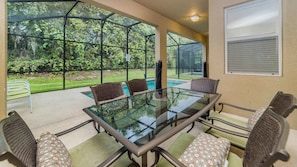 A glass-top table with six chairs, a pool, and a view of a wooded area. - Shv1185ha - 6 Bedroom Villa In Paradise Palms, Sleeps Up To 14, Just 6 Miles To Disney (Kissimmee)