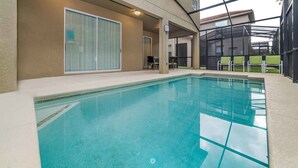 En inomhuspool med klart vatten, en täckt sittplats med stolar och en inglasad uteplats.