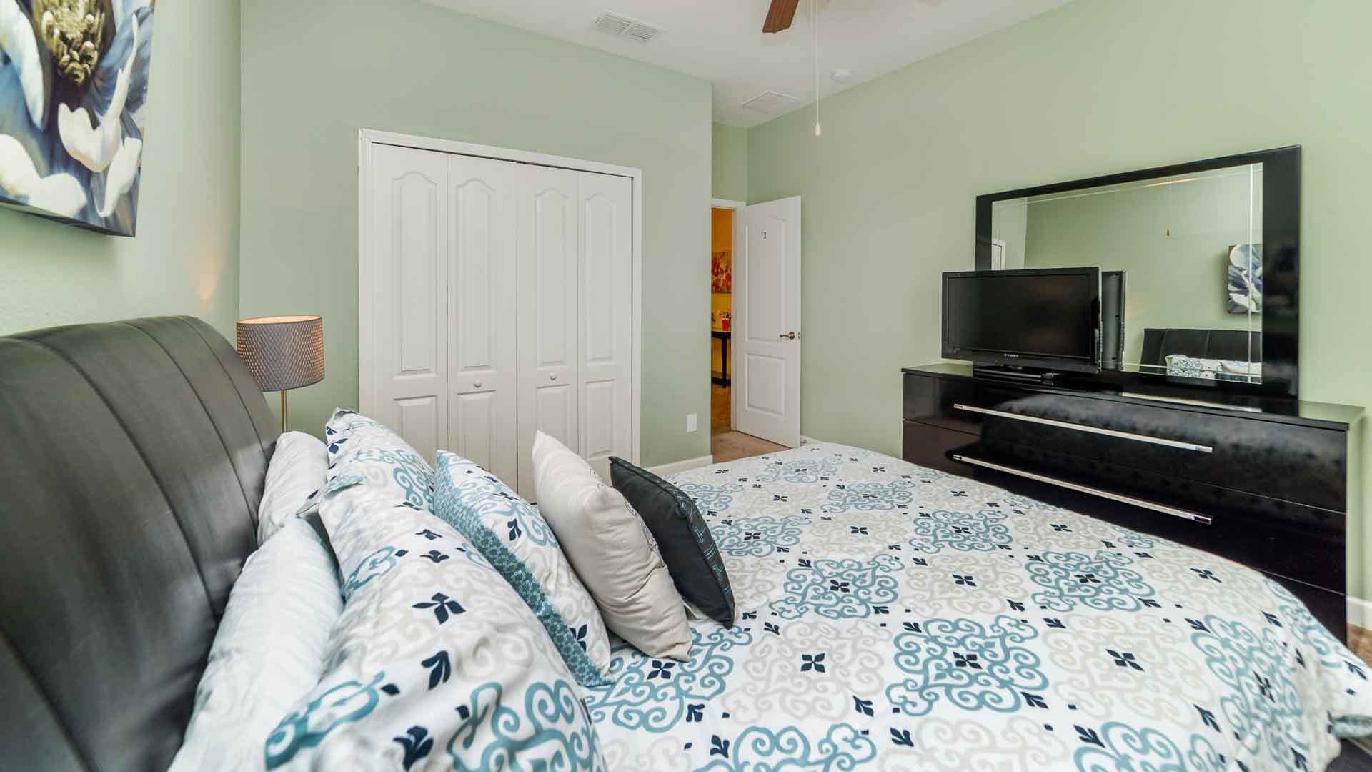 A bedroom with a bed, a TV, and a wardrobe.