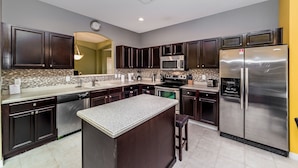 A modern kitchen with dark wood cabinets, stainless steel appliances, and a granite island.