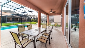 A covered patio area with a pool, outdoor seating, and a view of the surrounding landscape.