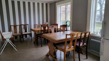 Een eetgedeelte met een houten tafel en stoelen, een radiator en een raam met uitzicht.