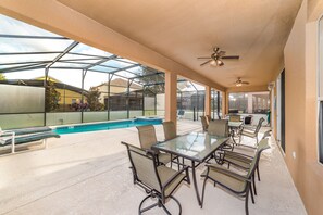 Ein überdachter Außenbereich mit Pool, Sitzgelegenheiten und Deckenventilator.