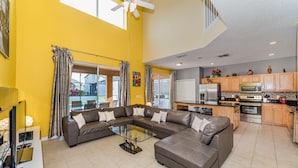 A spacious living room with a sectional sofa, a glass coffee table, and a large window with curtains. - Emerald Island #2 - 7 Bed 5 Baths Villa (Kissimmee)