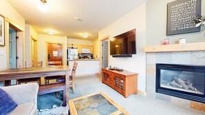 Een moderne woonkamer met een open haard, een eethoek en een keuken.