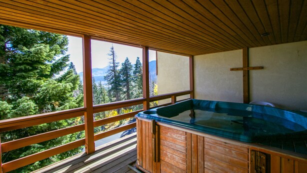 A wooden deck with a hot tub and a cross on the wall. - Bridges Townhome 7 Gorgeous Mountain Views, Private Jacuzzi, Steps to Eagle Lodge by RedAwning (Mammoth Lakes)