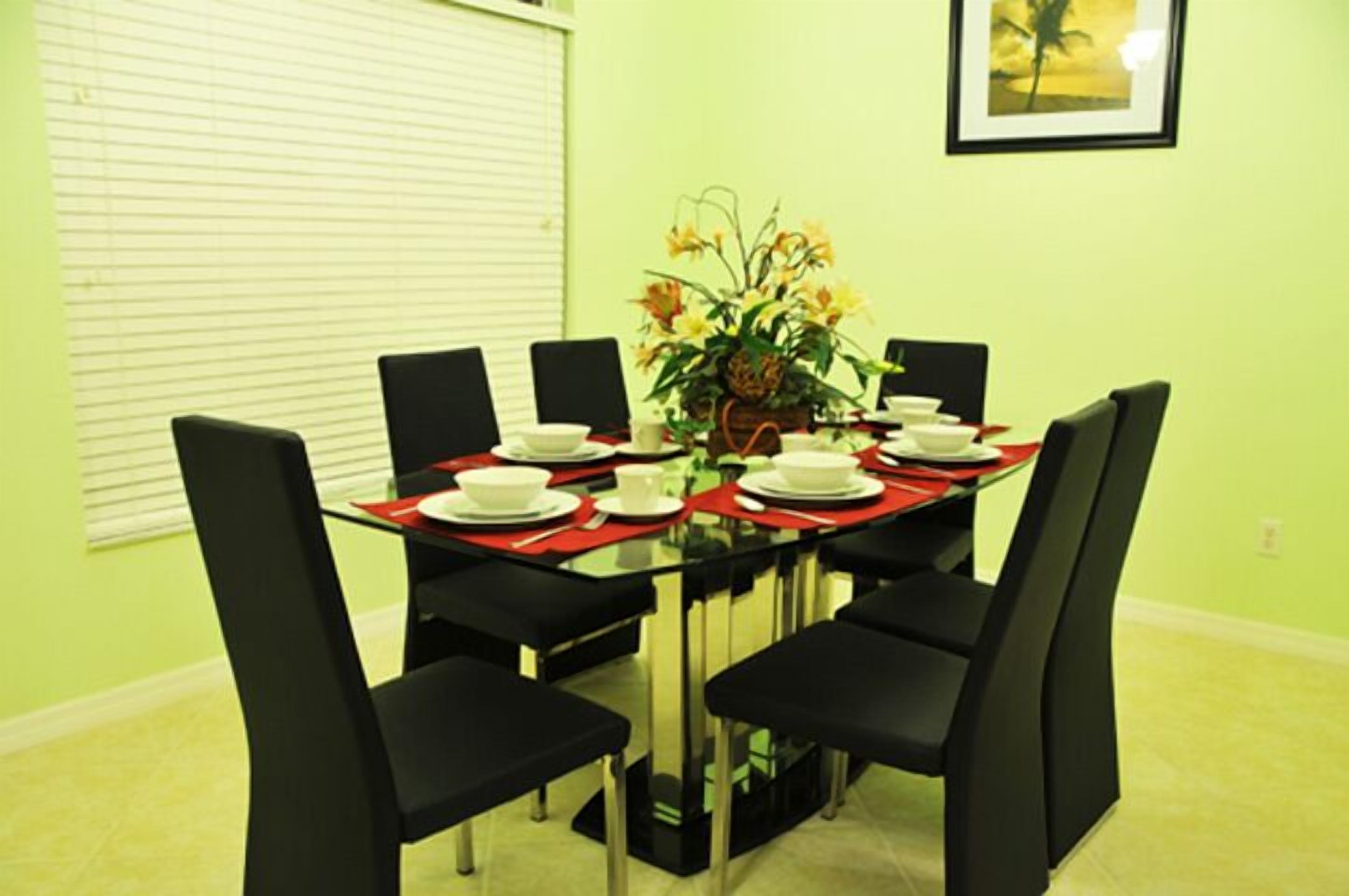 Un coin repas avec une table en verre, des chaises noires et un set de table rouge.