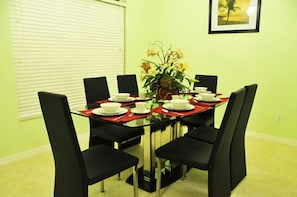 Un comedor con una mesa de vidrio, sillas negras y un mantel individual rojo.