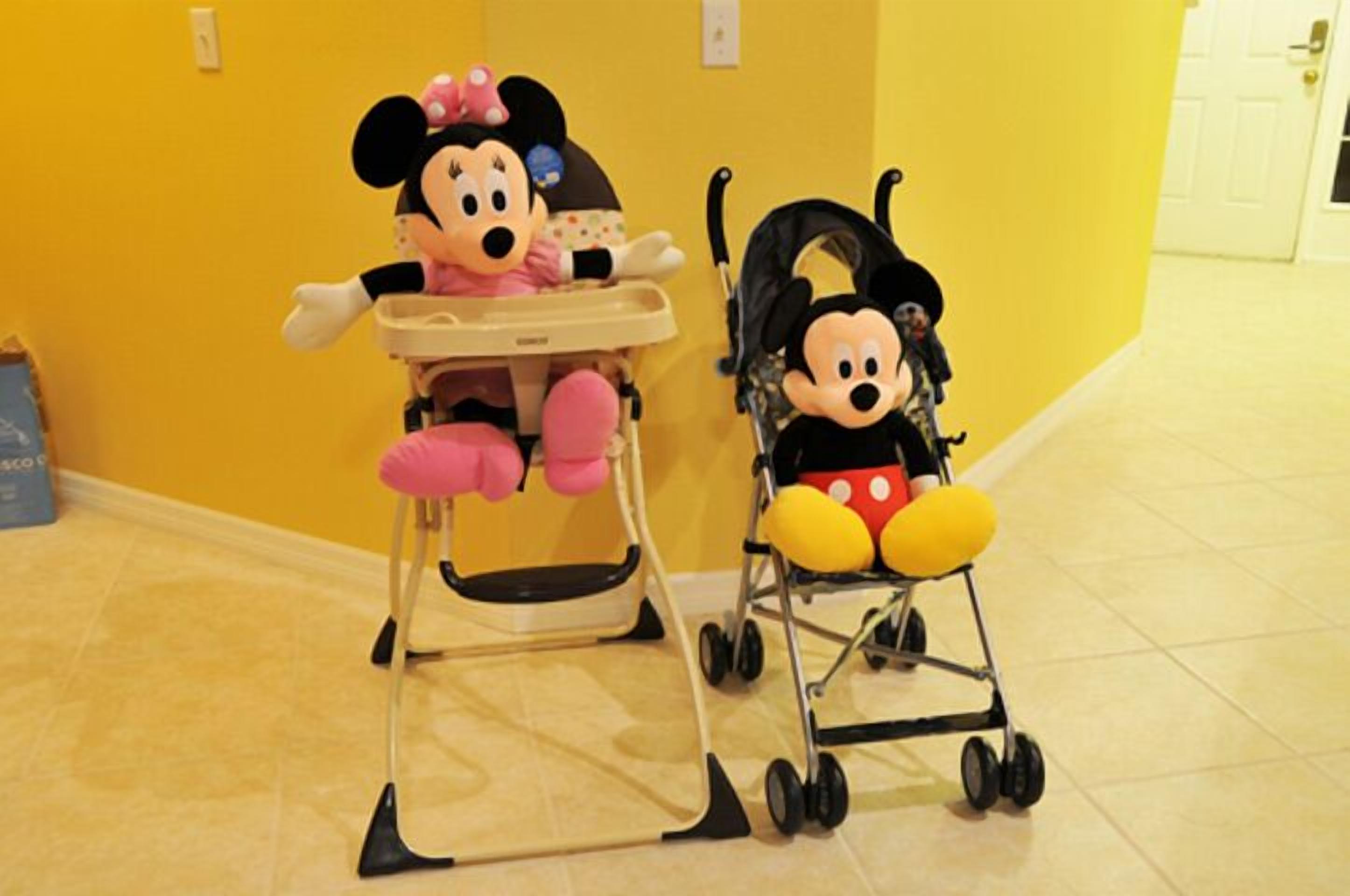 Une chaise haute pour bébé avec une poupée à l’effigie de Minnie Mouse et une poussette avec une poupée à l’effigie de Mickey Mouse.