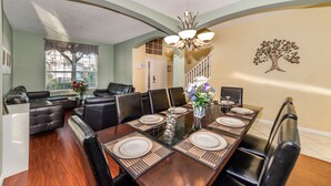 A dining area with a long table set for six, surrounded by black leather chairs.