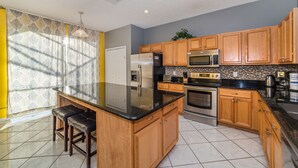 A modern kitchen with wooden cabinets, stainless steel appliances, and a black granite countertop.
