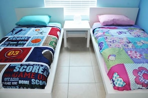 Une chambre à coucher avec deux lits simples, chacun recouvert d’une couvre-lit à motifs différents.