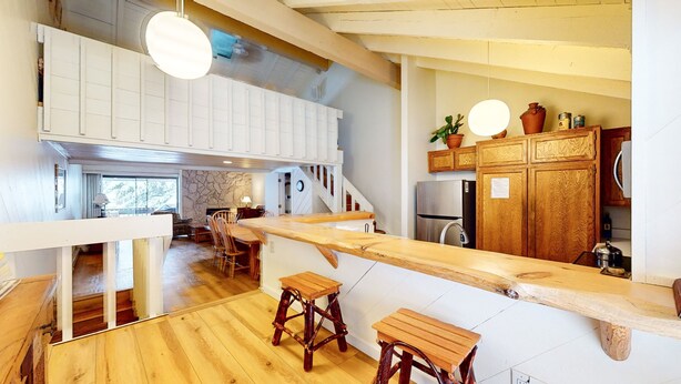 Una cocina moderna con taburetes de madera, un refrigerador empotrado y una pared de acento de piedra.