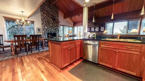 Una cocina con armarios de madera, lavavajillas y pared de piedra.