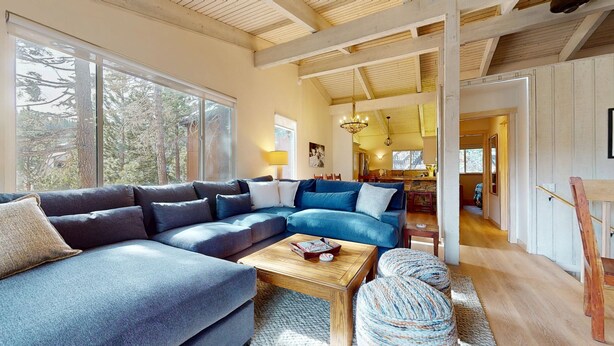 A modern living room with a sectional sofa, a coffee table, and a view of the kitchen and dining area. - Mammoth West 115 Updated Condo, Just A Short Walk To Canyon Lodge by RedAwning (Mammoth Lakes)