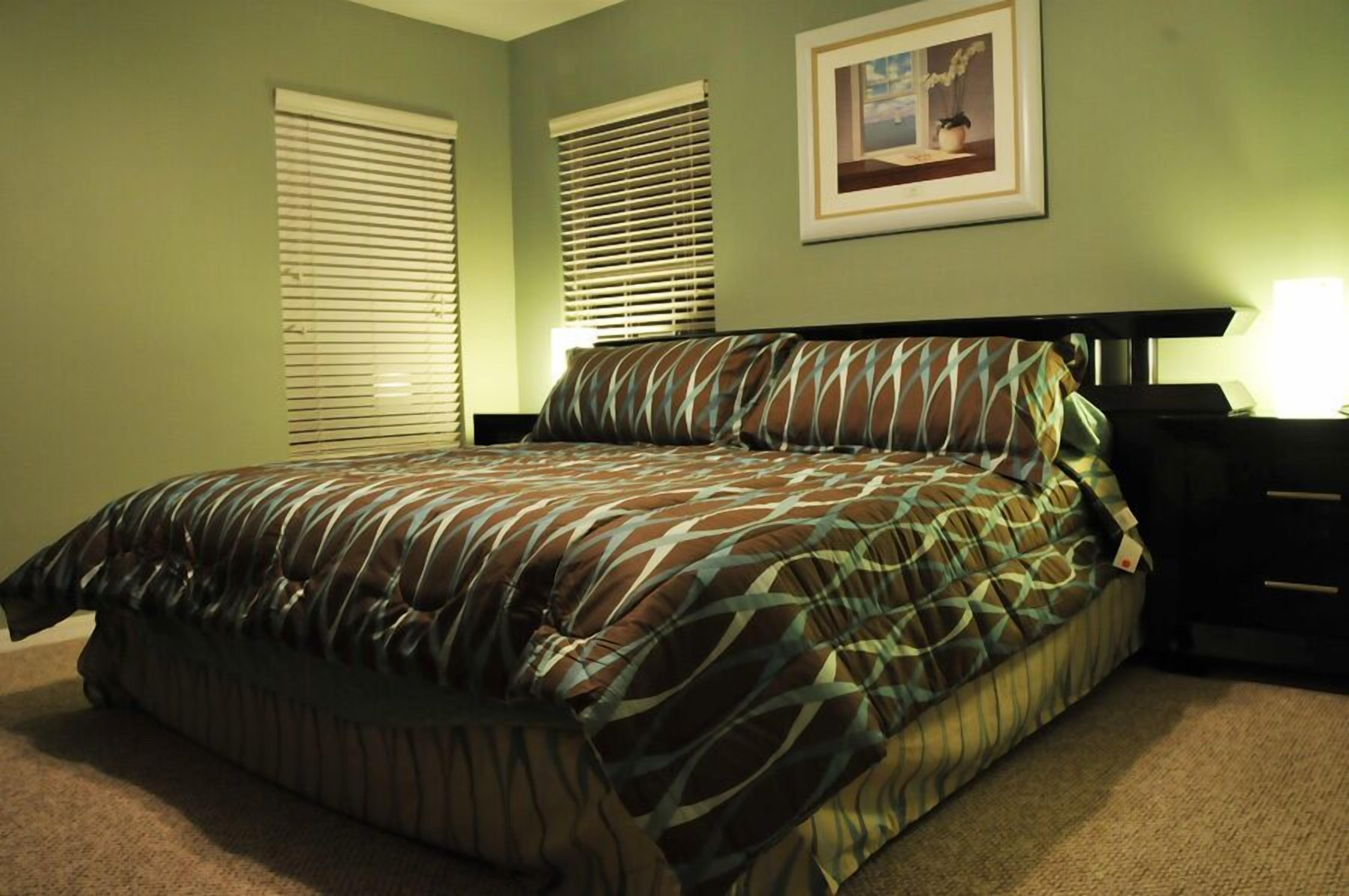 Una camera da letto con un letto, due comodini, una lampada e un quadro appeso al muro.