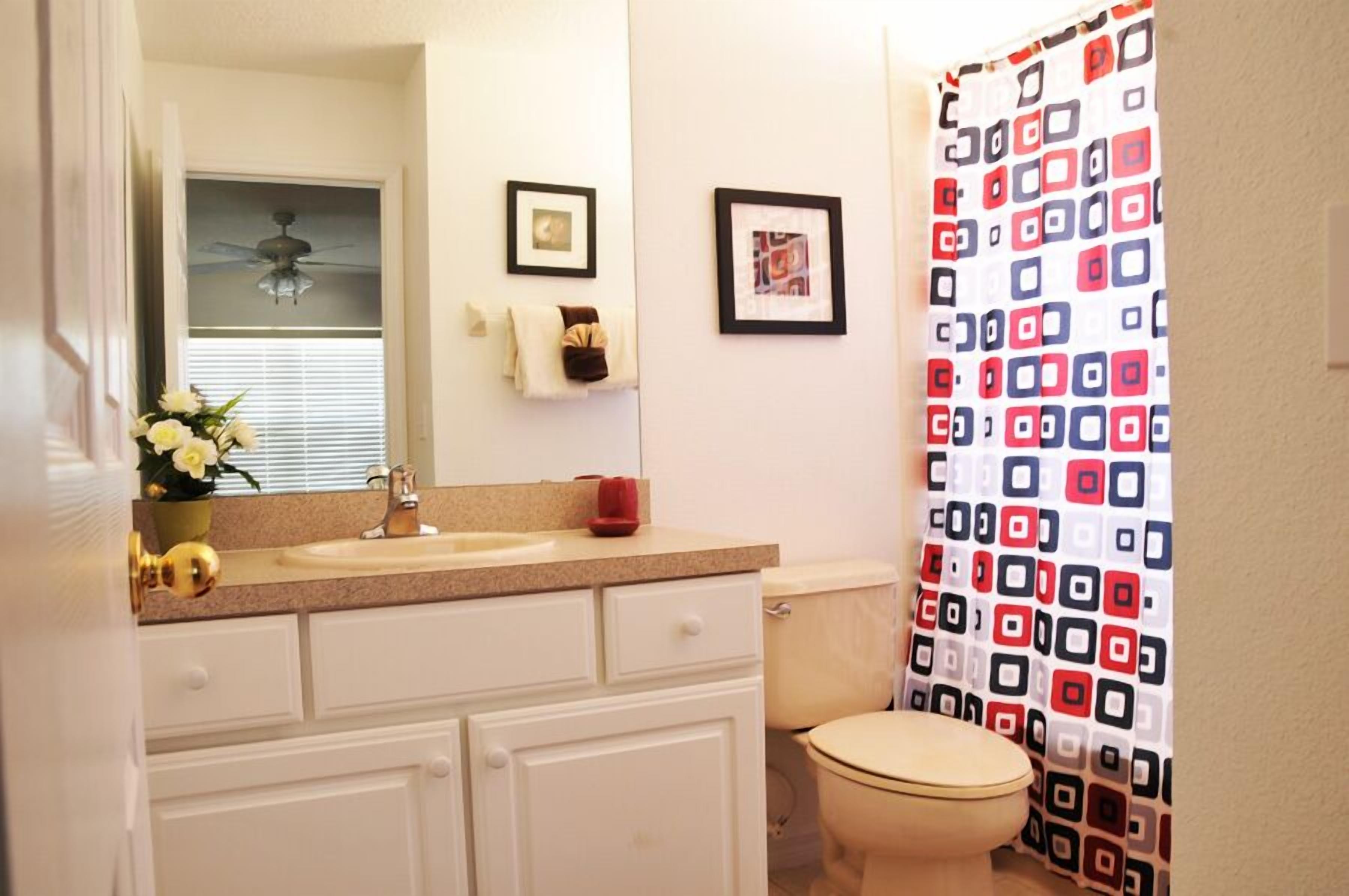 A bathroom with a toilet, sink, and shower curtain.